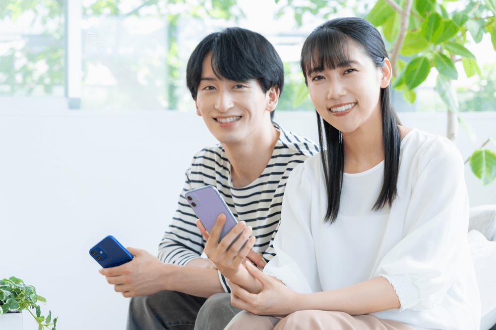 部屋でスマホを見る恋人同士